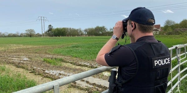PC Callum Barber surveying a field using binoculars after reports of fly-tipping