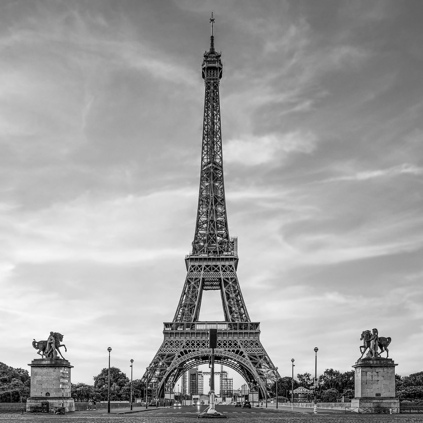 Black and white photo of the Eiffel Tower in Paris, France, taken from street level in the early morning.