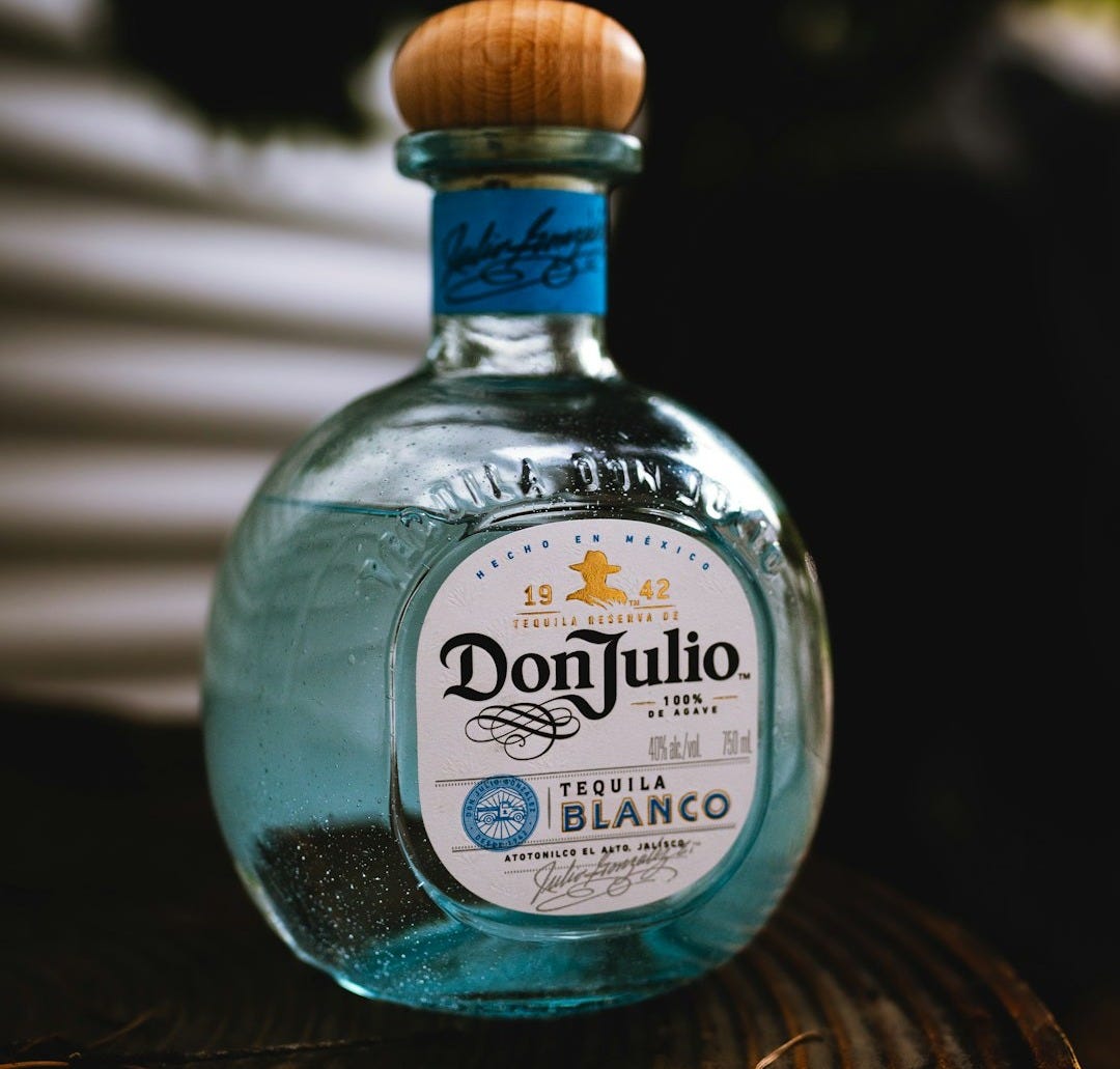 a bottle of tequila sitting on top of a wooden table a bottle of tequila sitting on top of a wooden table