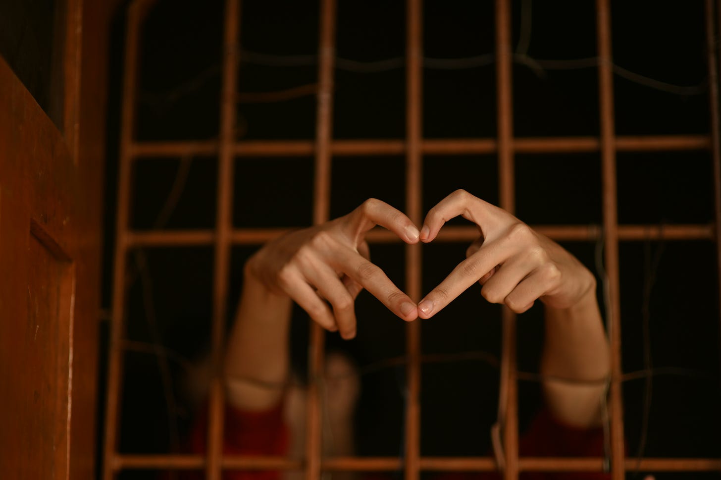 Hands extending from behind bars forming a heart