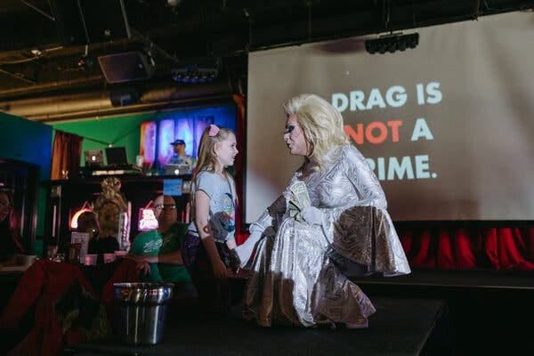 A drag artist speaks with a child onstage during a performance. 