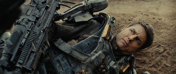 Tom Cruise in Edge of Tomorrow, lying on the ground in a robotic combat suit with an exasperated look on his face.