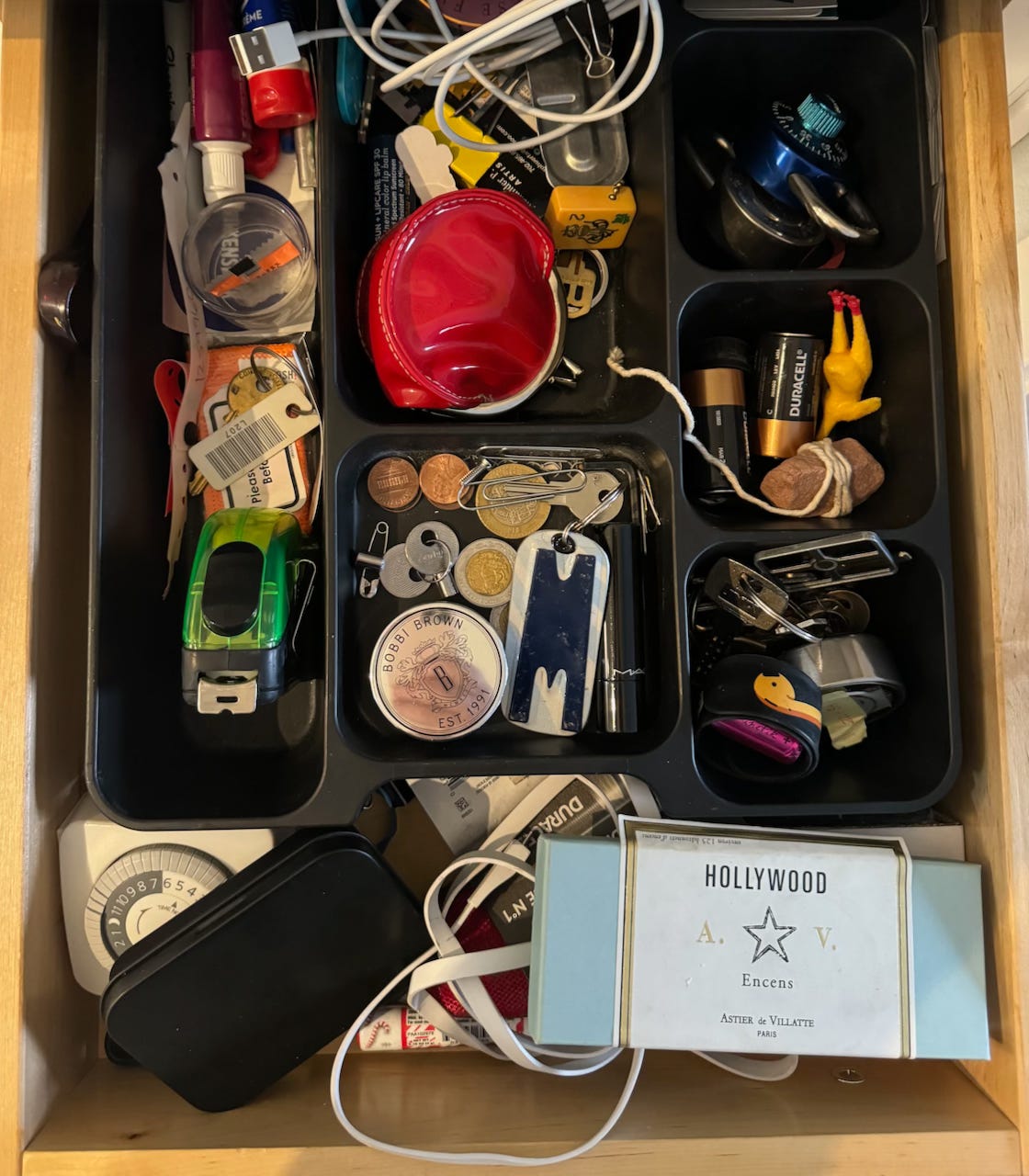 A messy drawer pulled open to reveal its contents.