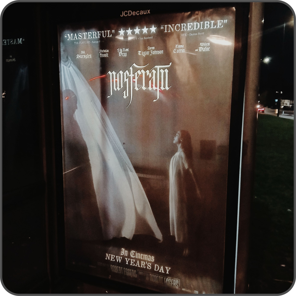 An atmospheric poster for 'Nosferatu' at a bus stop, gothic artwork and text