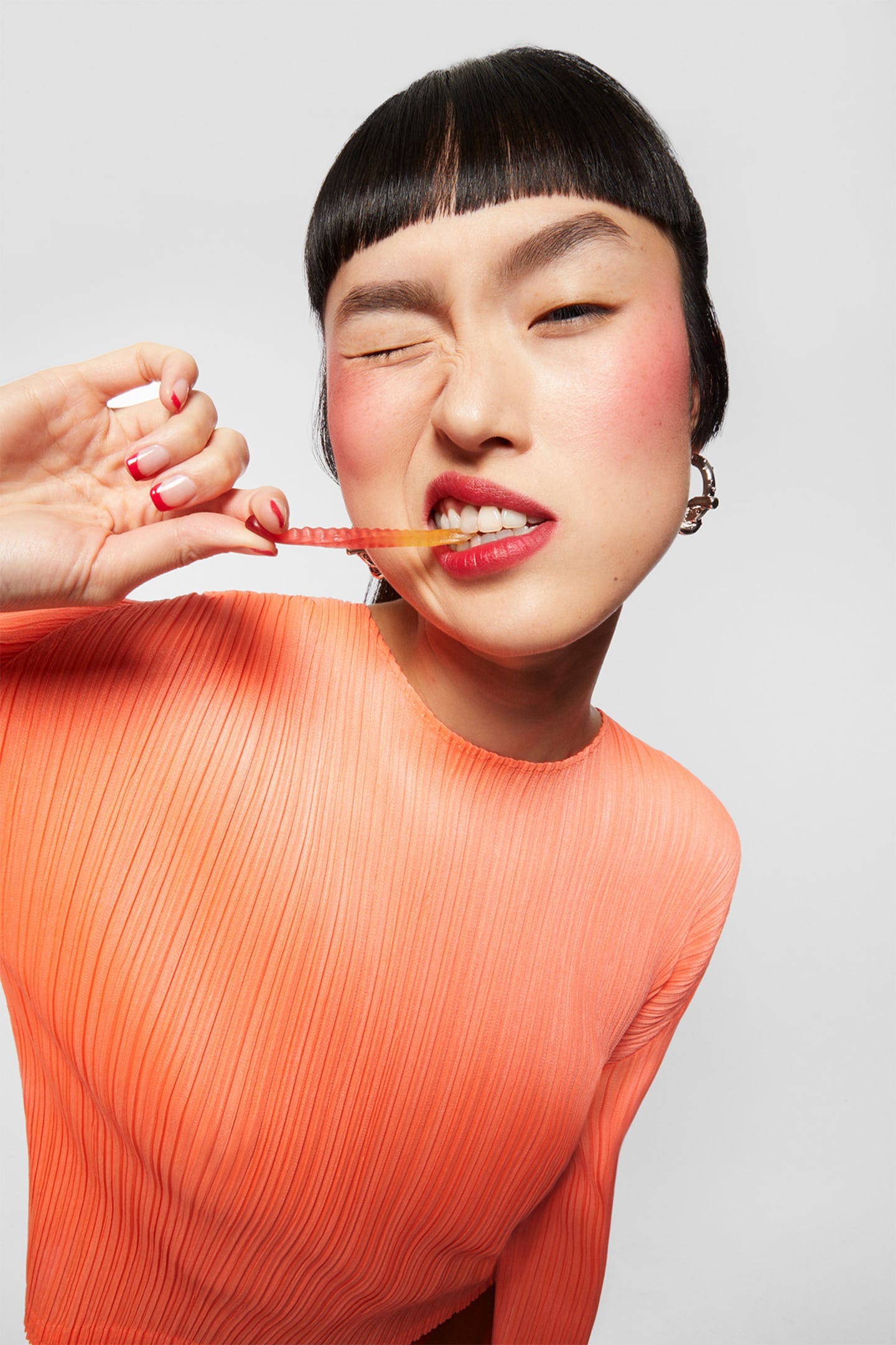 A model taking a bite out of a gummy worm