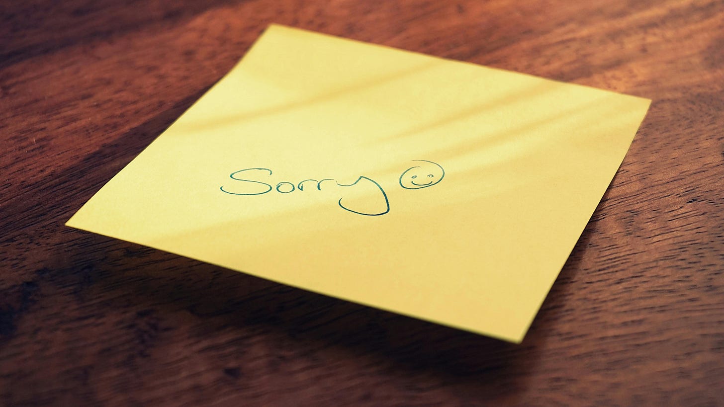 Sorry written on yellow envelop on brown table