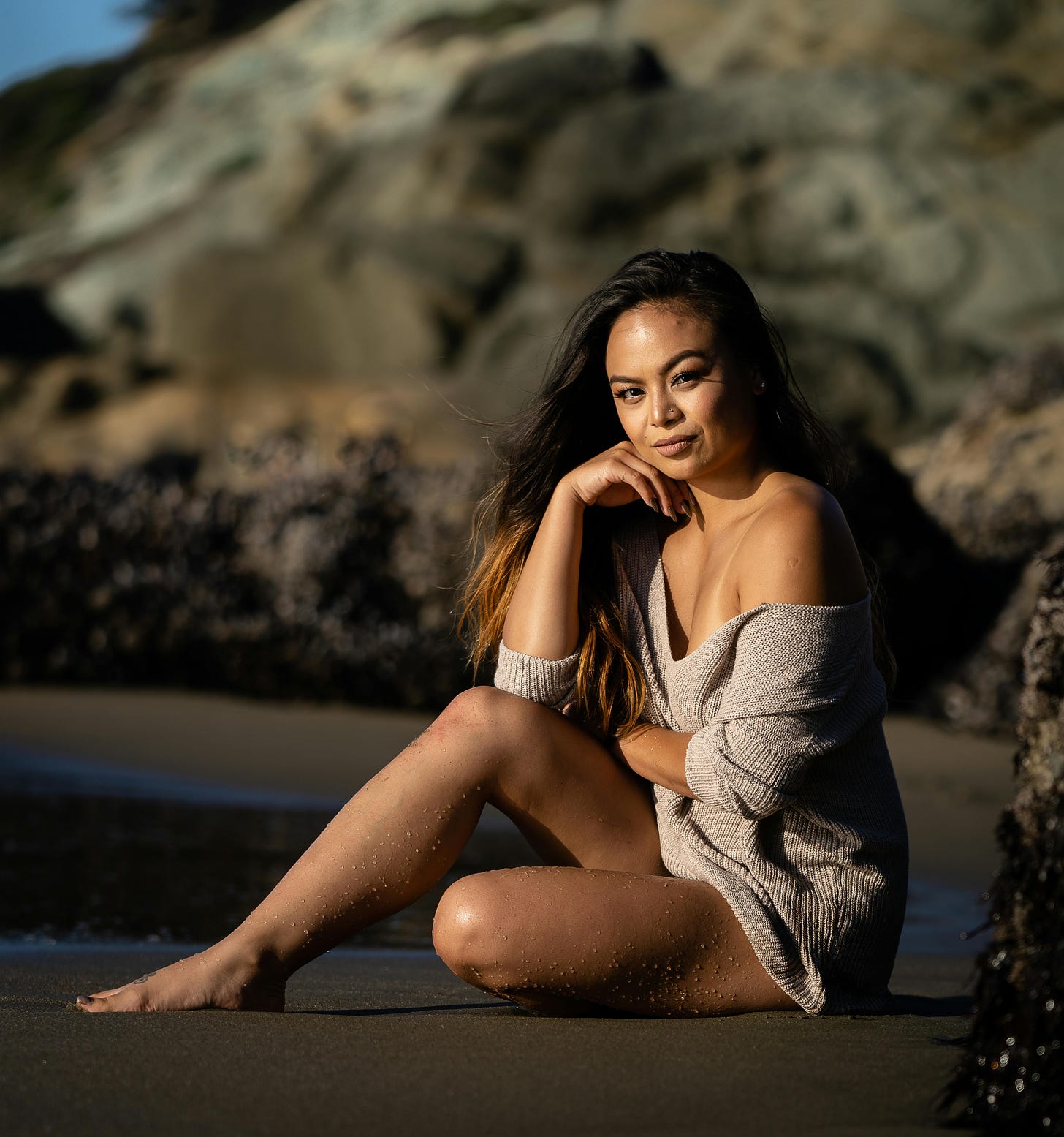 Woman long hair sitting on beach in knit outfit