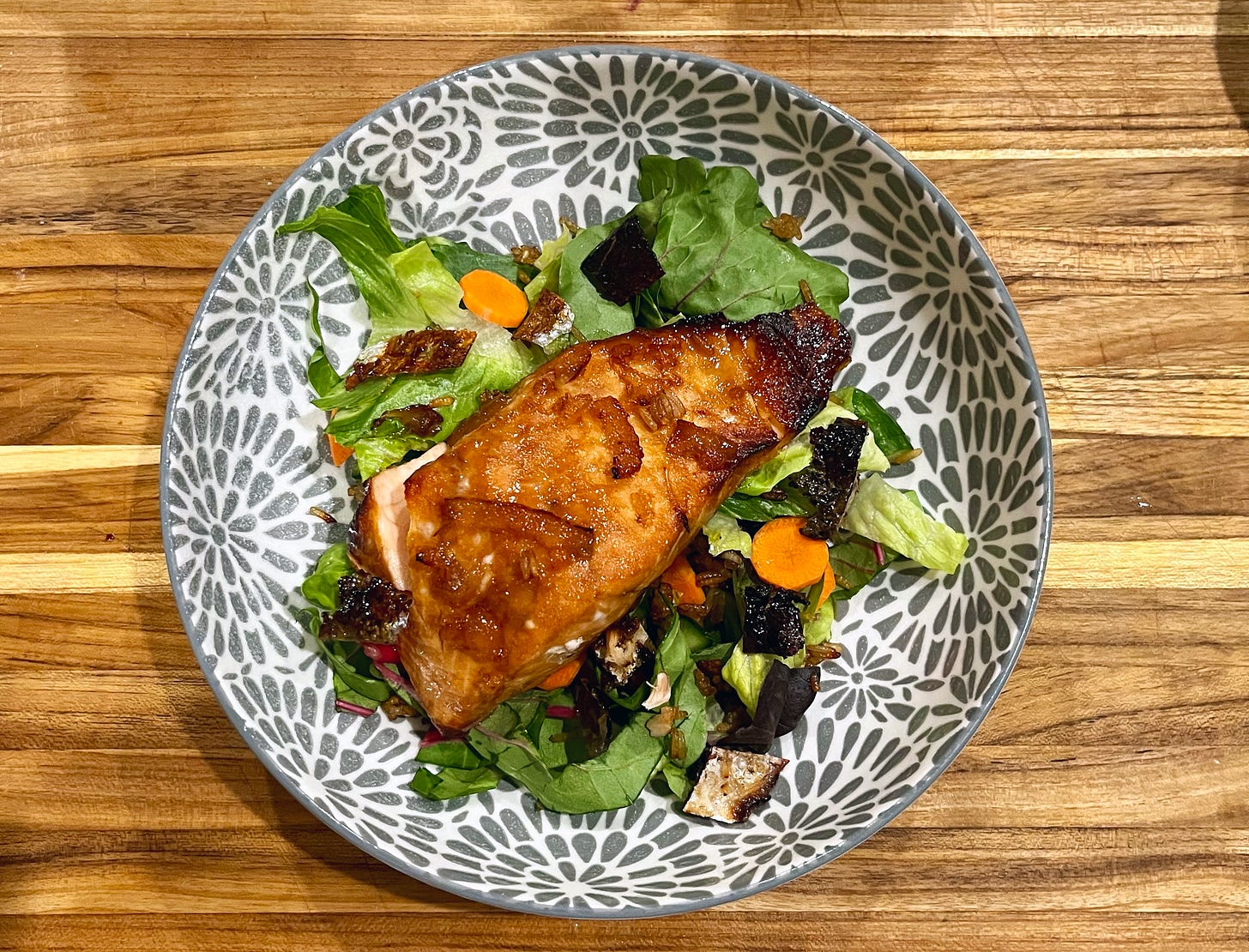 A coconut aminos and yuzu marinated salmon with crispy salmon skin on a leafy salad.