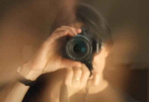 Blurred sepia image of man with hands on zoom ring on camera