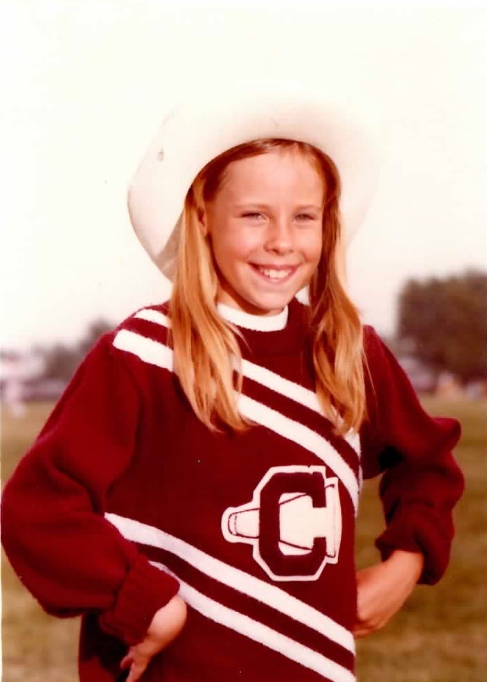 Young blonde girl with pigtails smiles while wearing a maroon sweater with a white megaphone and the letter "C" Young blonde girl with pigtails smiles while wearing a maroon sweater with a white megaphone and the letter "C"