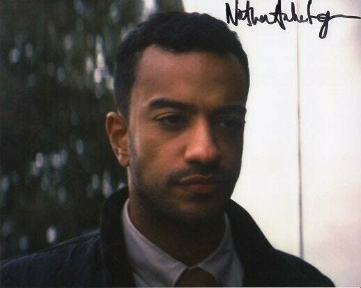 This autographed photo shows Nathan Armarkwei-Laryea in character as Armen, a government truck driver, in "Revolution of the Daleks" (Doctor Who's 2021 New Year's Day Special). Armarkwei-Laryea's signature appears in the photo's upper-right corner. This autographed photo shows Nathan Armarkwei-Laryea in character as Armen, a government truck driver, in "Revolution of the Daleks" (Doctor Who's 2021 New Year's Day Special). Armarkwei-Laryea's signature appears in the photo's upper-right corner.