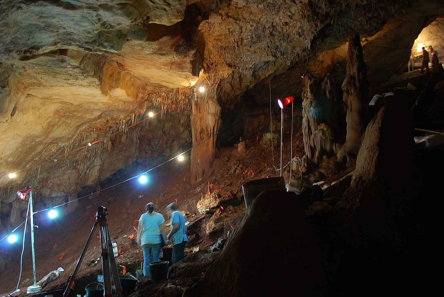 Manot Cave with sloping sediment, archaeologists, and lights Manot Cave with sloping sediment, archaeologists, and lights