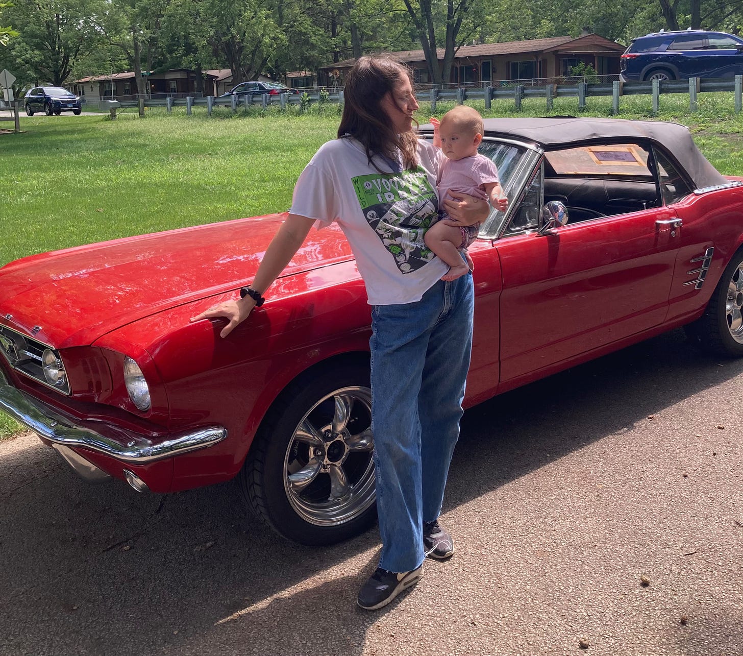 Me and baby standing in front of a 1966 red Mustang