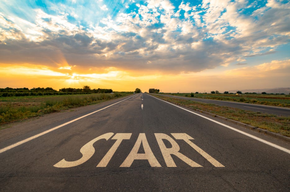 A road stretching forward with the word “START” painted on the pavement, symbolizing momentum and taking the first step.