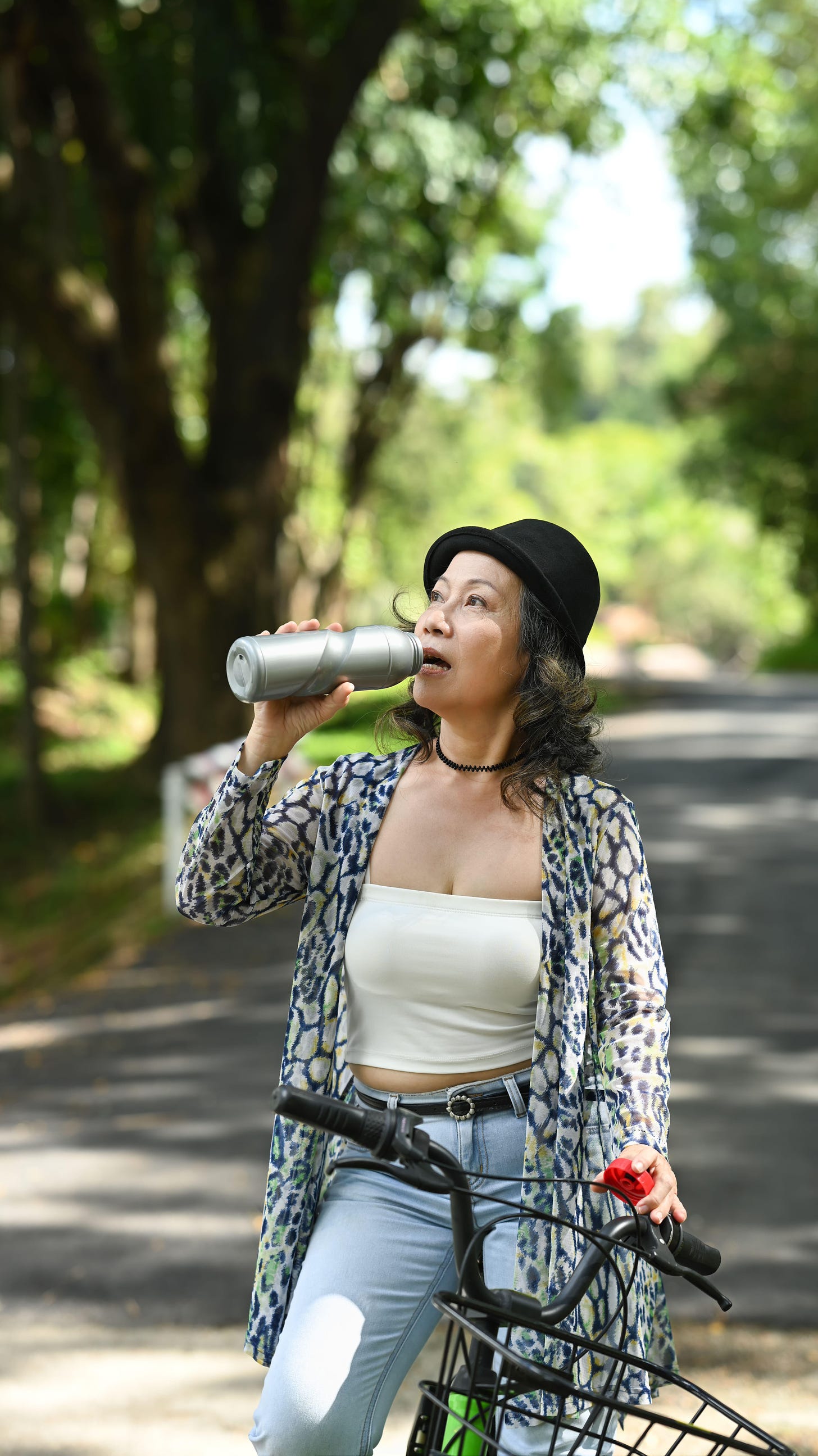 Middle aged woman pausing her cycle in the park to drink some water