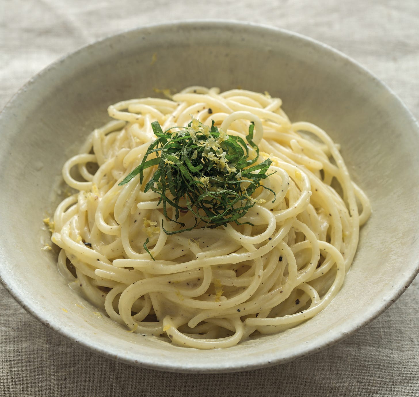 light gray bowl of udon al yuzu kosho with shiso on top