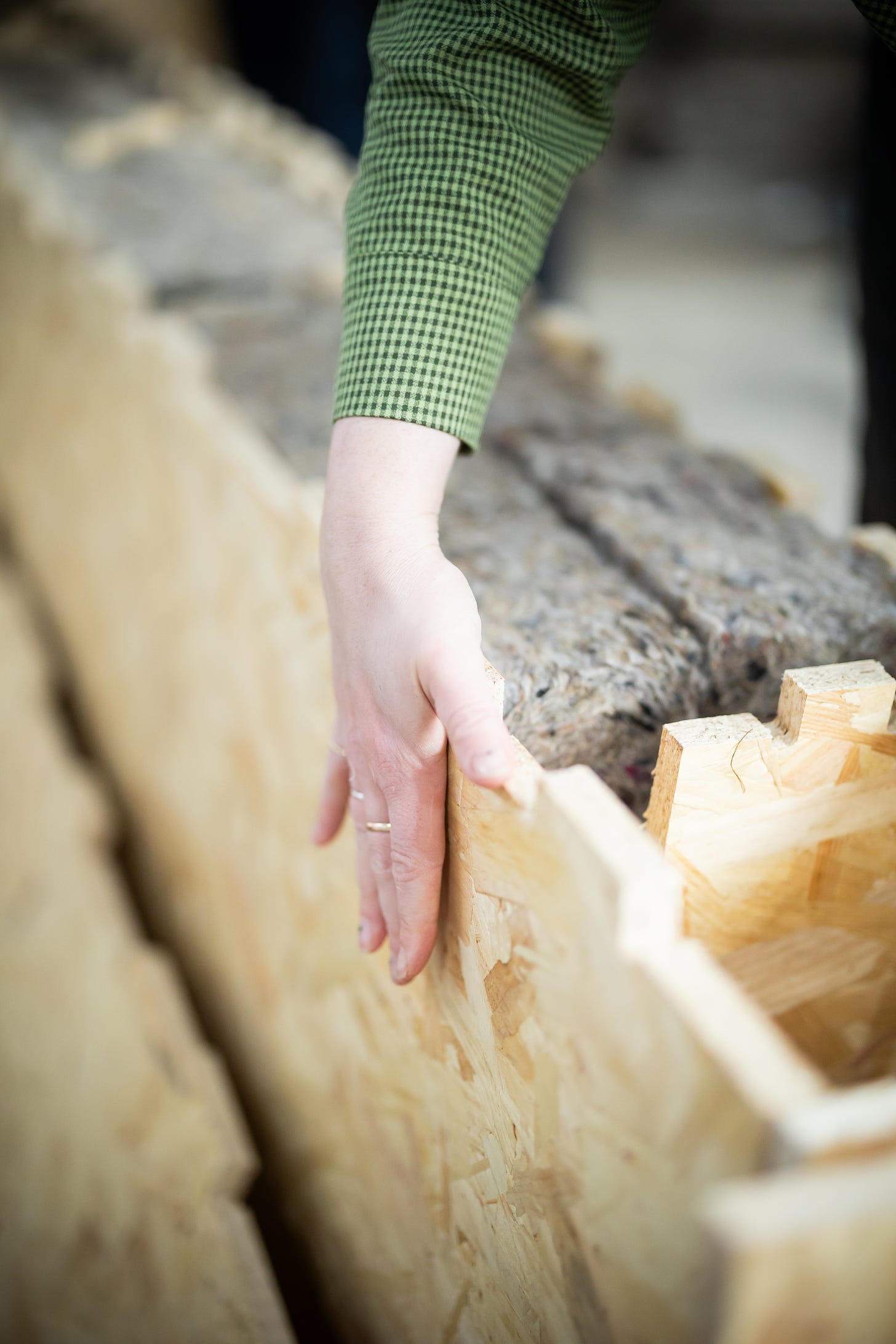 A hand is touching an open WikiHouse block. The block is made of OSB and insulated with natural fibres.