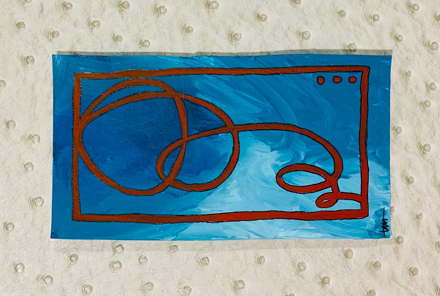 A completed work of art from Bad Art Club. On a long rectangle of multicolor blue, a burgundy squiggle is contained in a burgundy box, with 3 burgundy dots in the top corner. The art is on a white faux ostrich skin background.