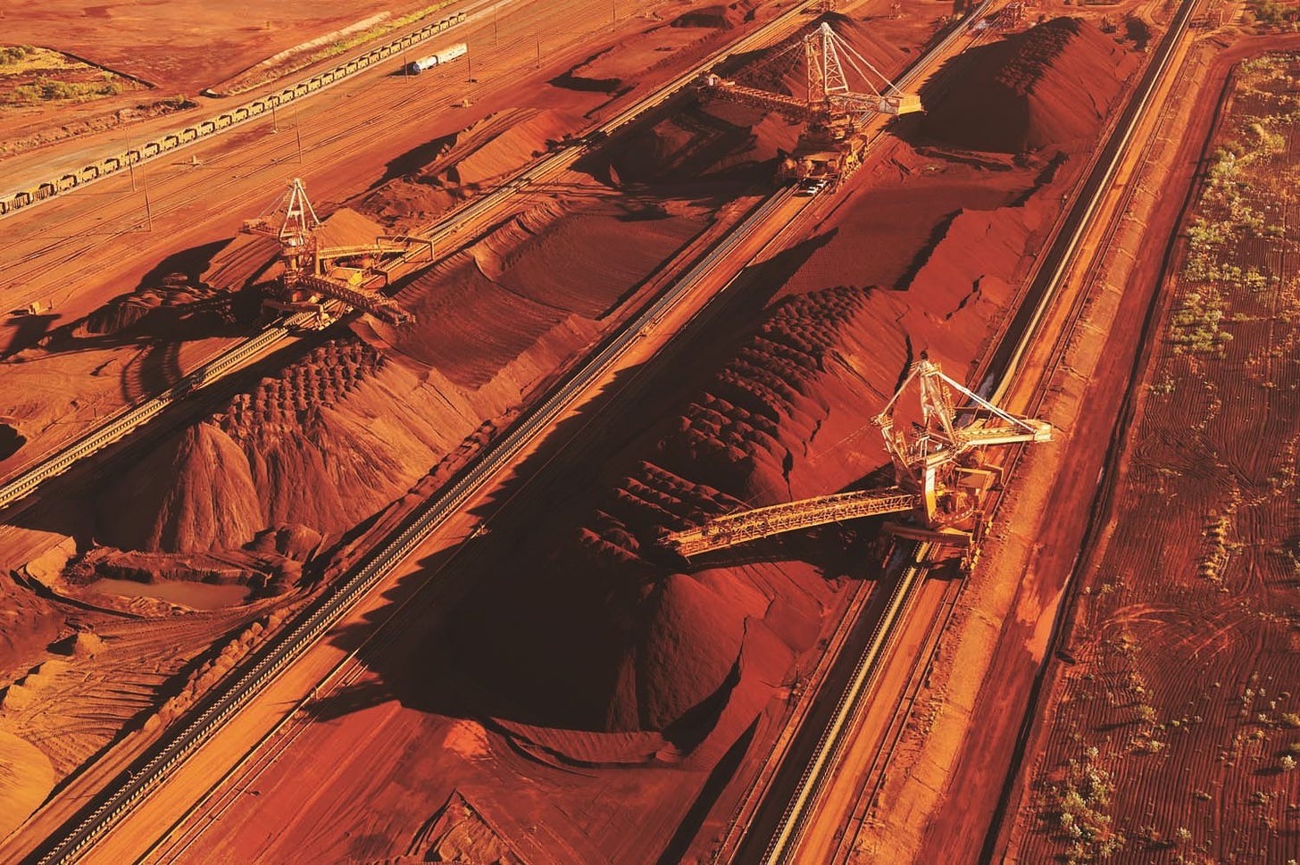 Heavy equipment working in a red landscape of iron ore.