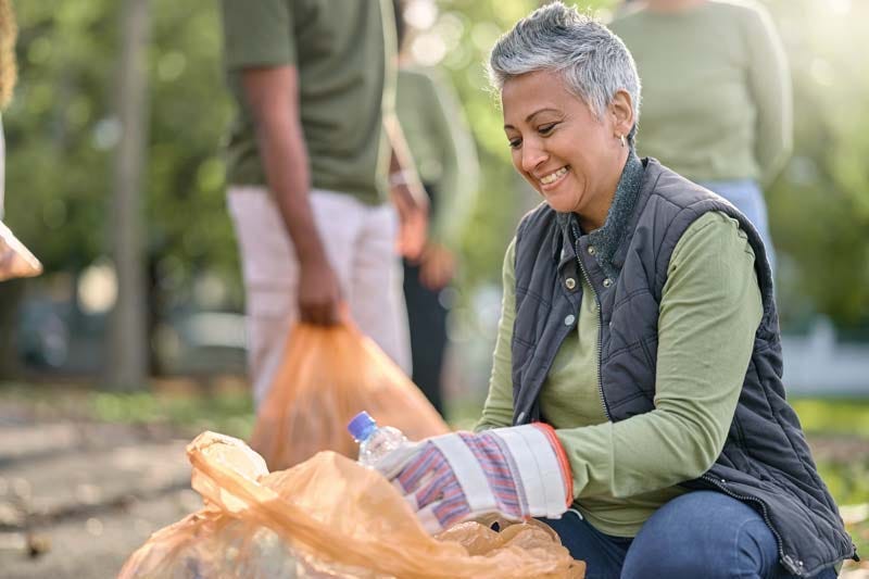 Active elder woman volunteering with friends to clean up local park