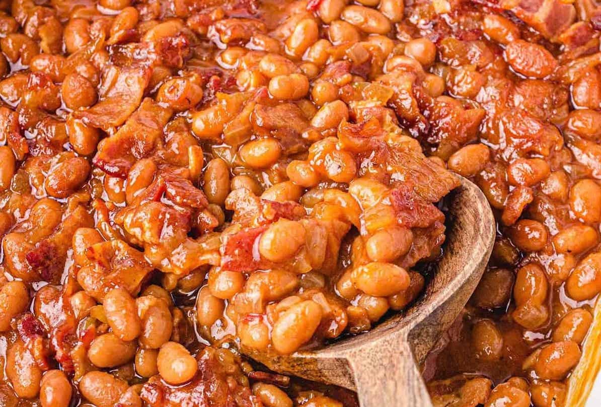 Closeup picture of baked beans with wooden spoon.