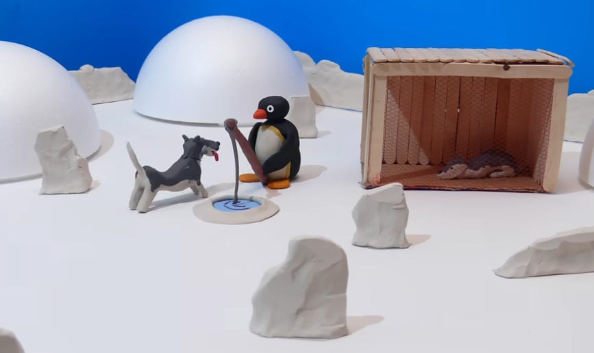 frame do vídeo paródia do Pingu com The Thing. Nele, num cenário feito em massinha e palitos de sorvete, o Pingu, um pinguim, está pesando num buraco no gelo, com um husky com a língua pra fora do lado. O cenário é de uma cena de neve. Ao lado direito dos dois, há um abrigo de cachorros feito com palitos, com outro husky dormindo lá dentro. 