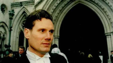 Keir Starmer/Tom Baldwin Sir Keir Starmer, dressed formally in his court silk gown, stands outside the Royal Courts of Justice in central London in 2006