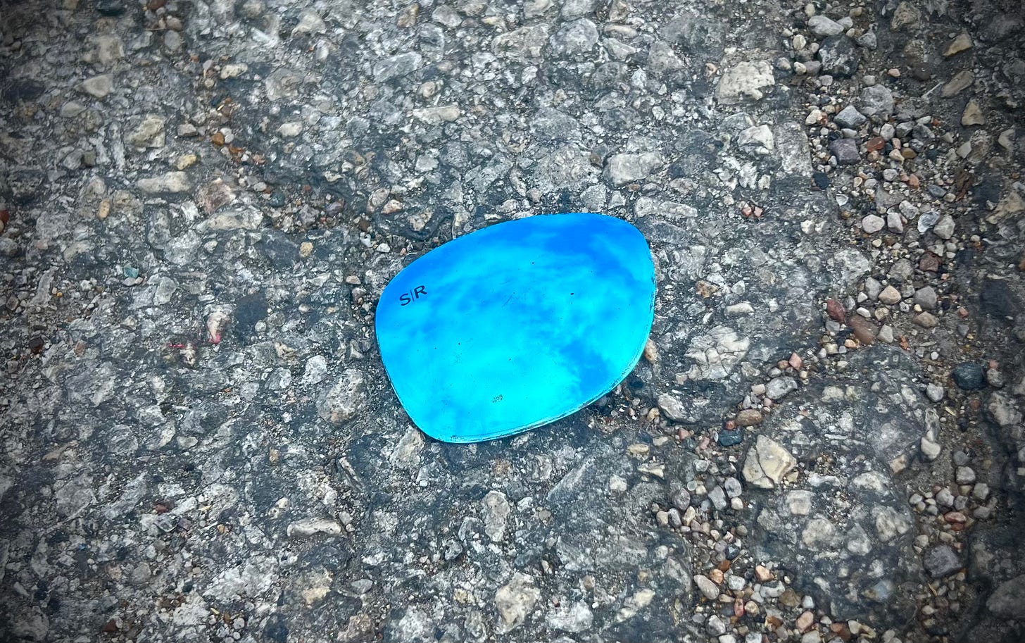 Blue mirrored sunglass lens on asphalt