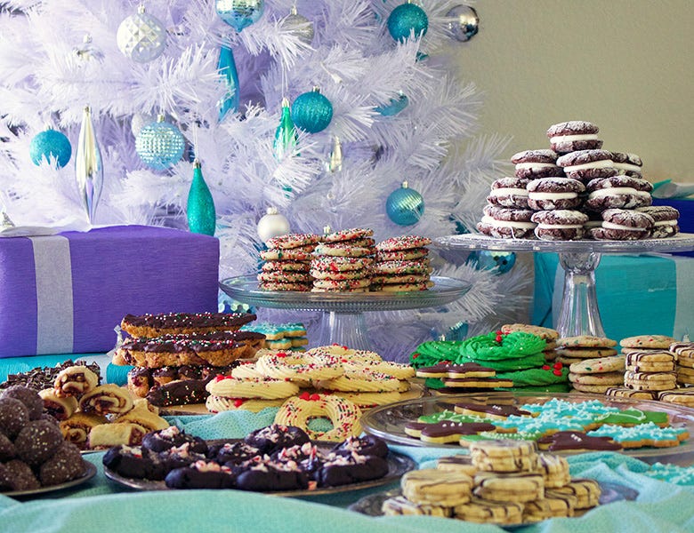 A table spread with plates of Christmas cookies