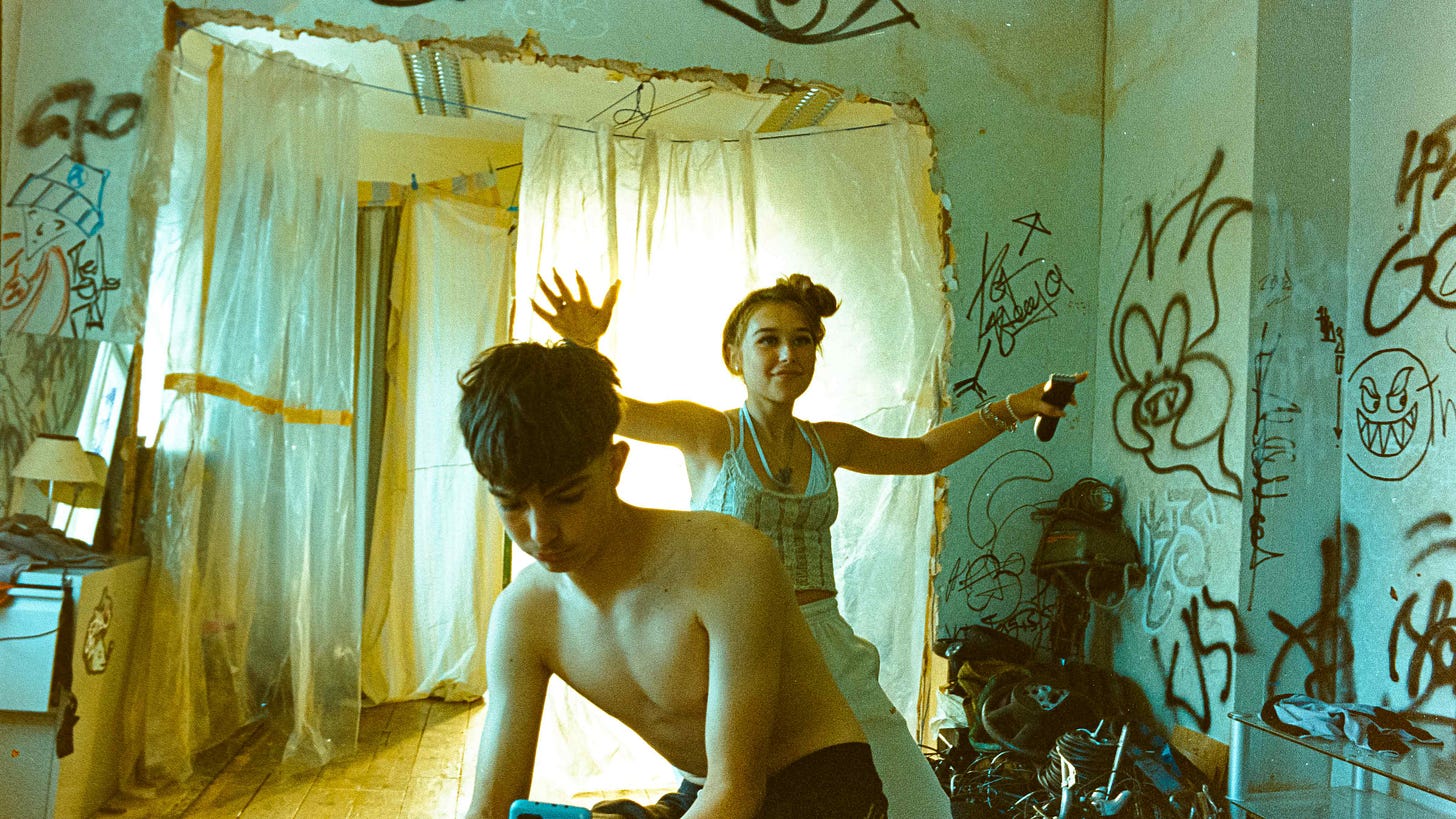 Two teenagers Hunter (Jason Buda) and Moon, posing in front of a window with plastic sheets hanging from the ceiling and walls covered in graffiti.