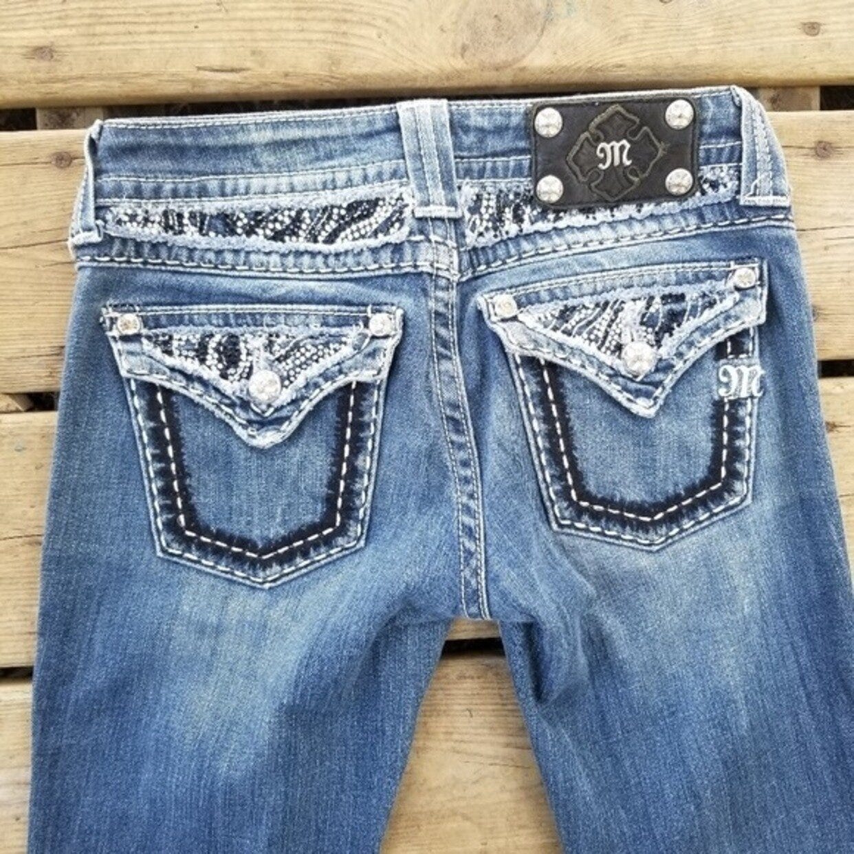 Pair of blue jeans with excessive white stitching and jewels on the butt