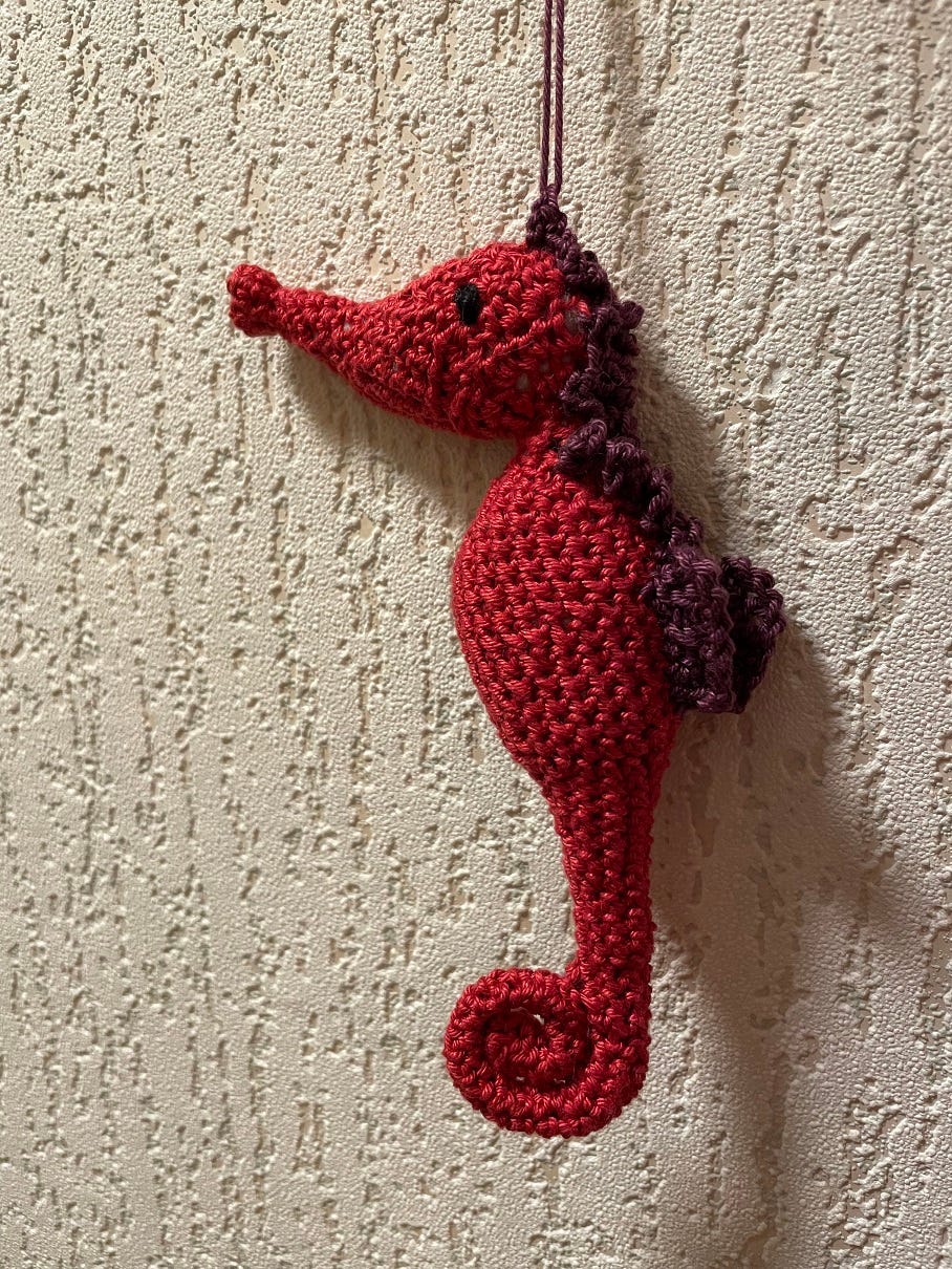 Photo of a crocheted seahorse in red and purple yarn