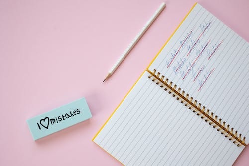 Free Crossed Out Words in Notebook Lying on Pink Surface Stock Photo