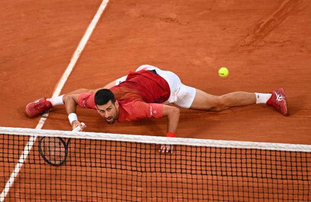 Novak Djokovic of Serbia falls after stretching for a forehand against Francisco Cerundolo of Argentina in the Men's Singles fourth round match...