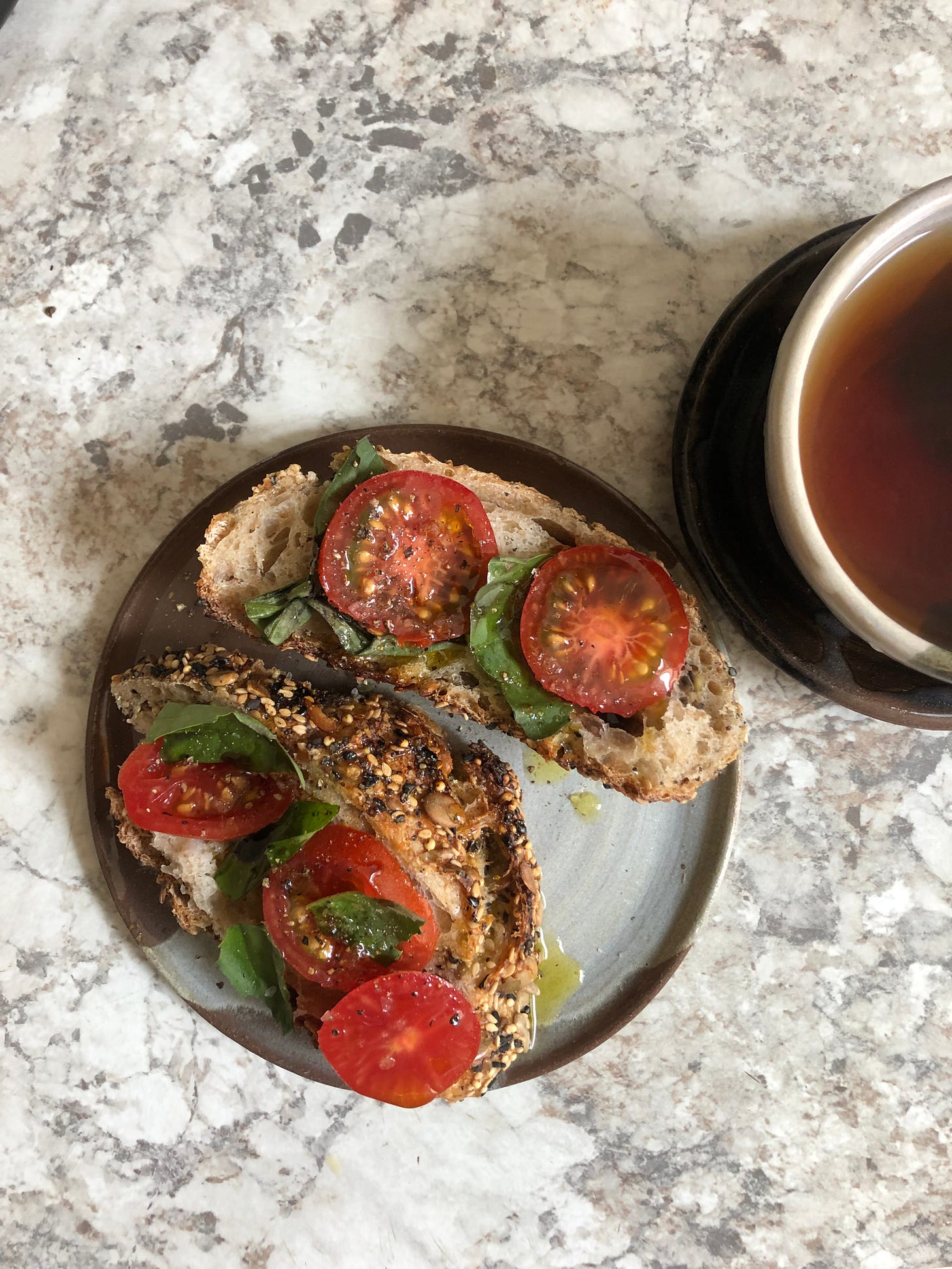 Tomato on sourdough drizzled in olive oil and garnished with basil, fresh cracked pepper and flakey salt.