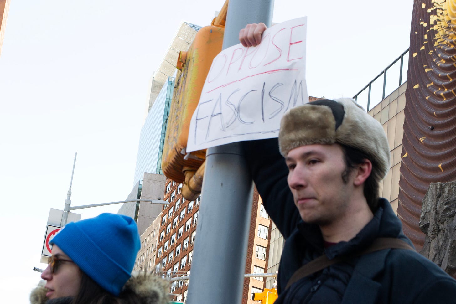 A man holds up a sign that says "oppose fascism."