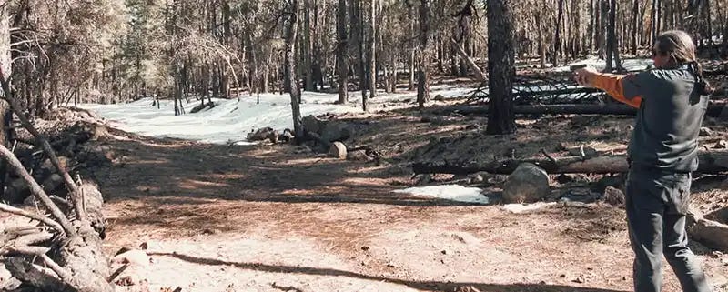 photo of someone shooting a gun while camping