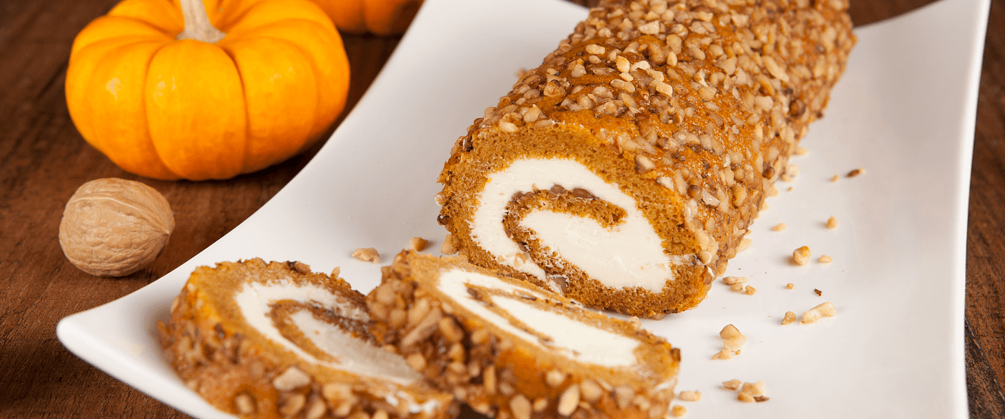 A pumpkin swiss roll cake ona. white platter.