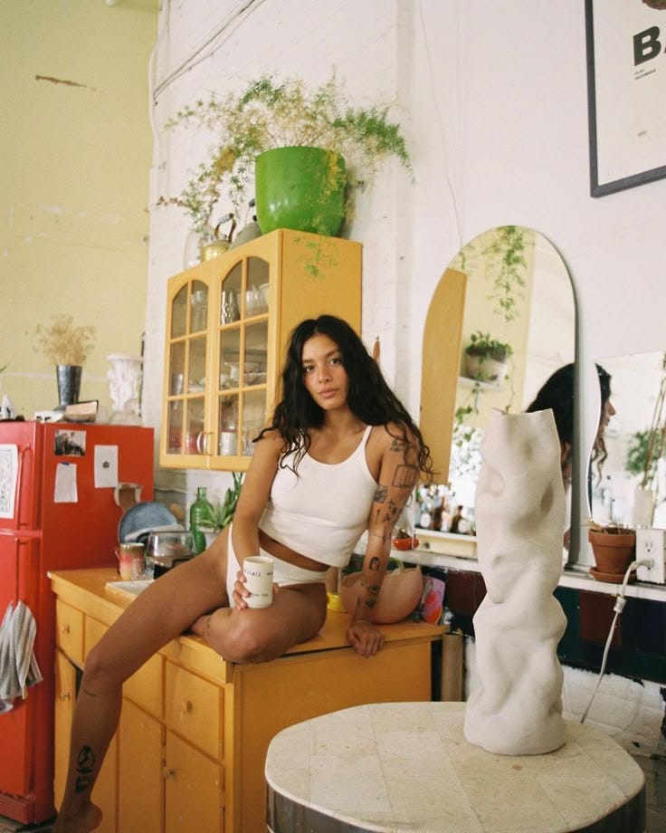 This may contain: a woman sitting on top of a table next to a vase