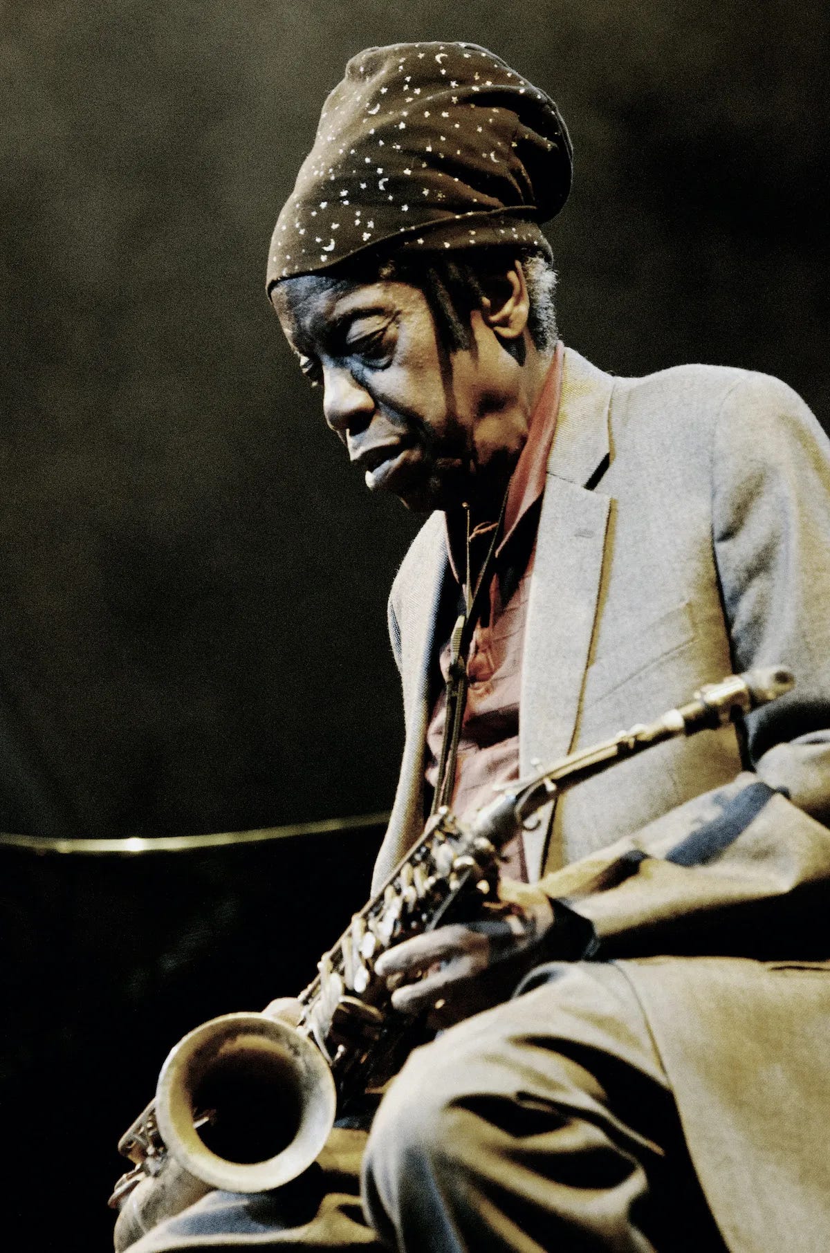 Jemeel Moondoc sitting on a stool holding his saxophone