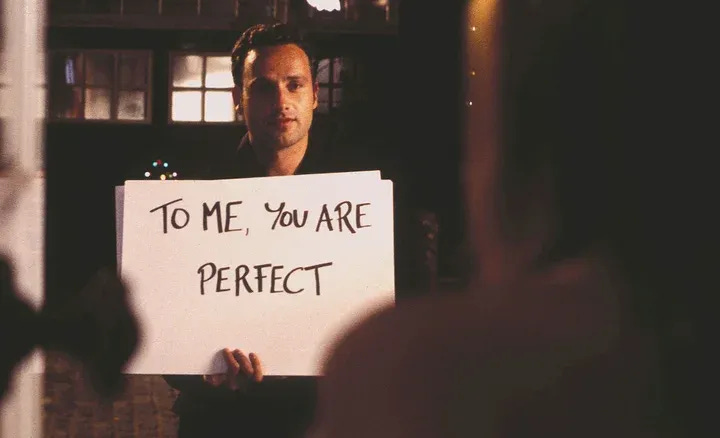 Still from Love Actually with Andrew Lincoln holding a sign which reads to me, you are perfect.