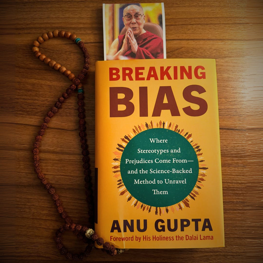 A book with a yellow cover on a wooden table with a photo of the Dalai Lama