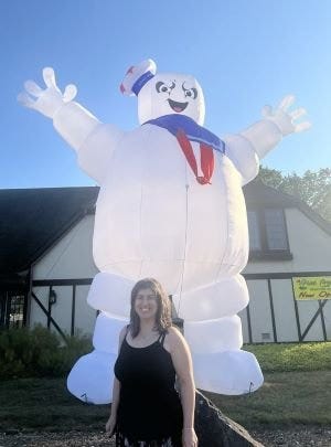 Dawn standing in front of a very large blow up stay puffed marshmallow man from the ghostbusters movie