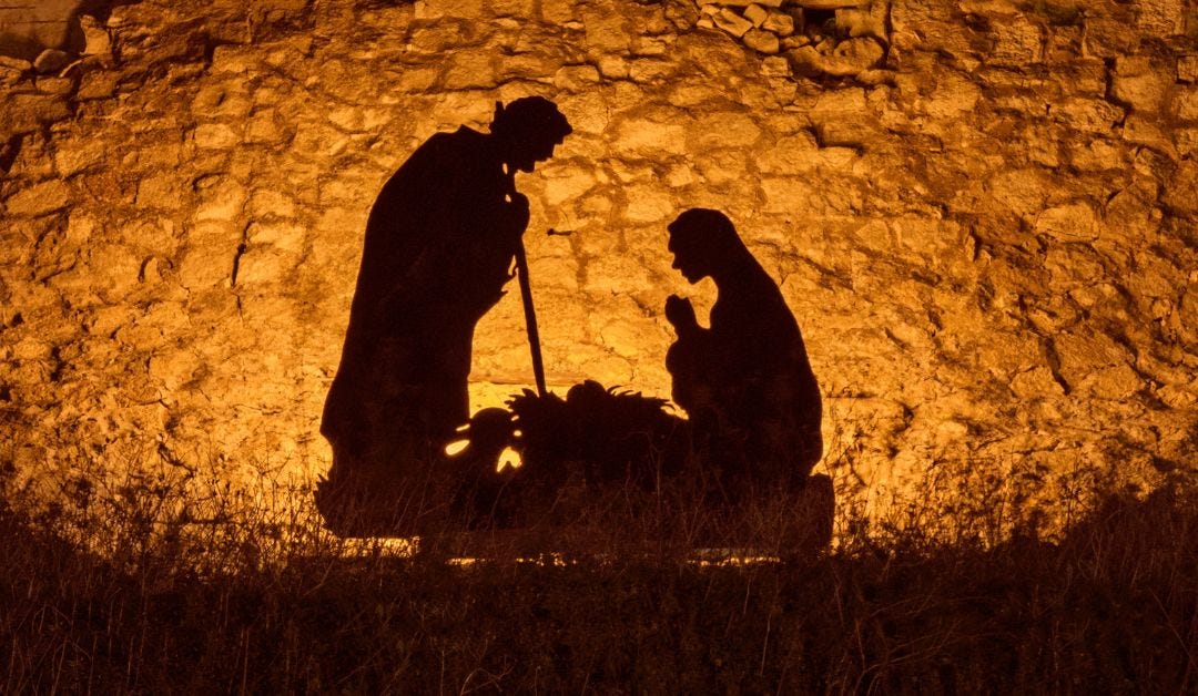The shadows of Joseph, Mary and the manger projected at stone wall