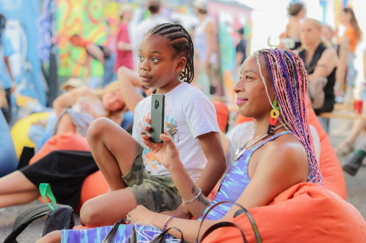 A woman and girl sitting on bean bags watching a show