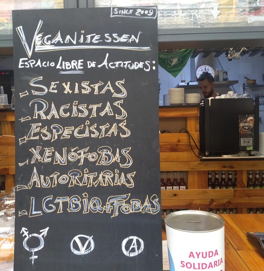 A chalkboard in front of a till that says 'Veganitessen is un espacio libre de sexismo, racistas, especcistas, xenofobas, autoritarias, lgbtiq+fobas
