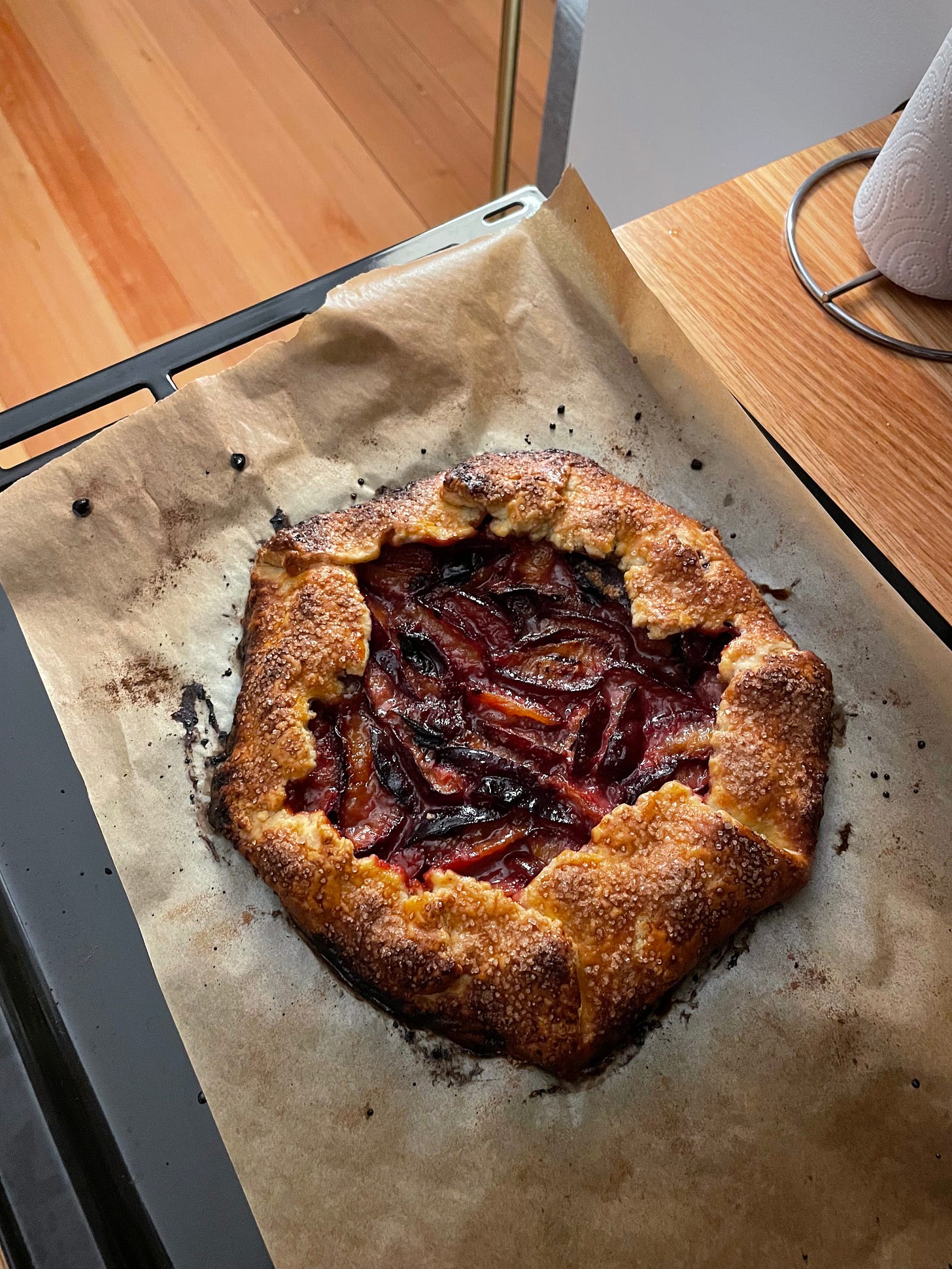 Plum and almond galette cooling on a kitchen counter.