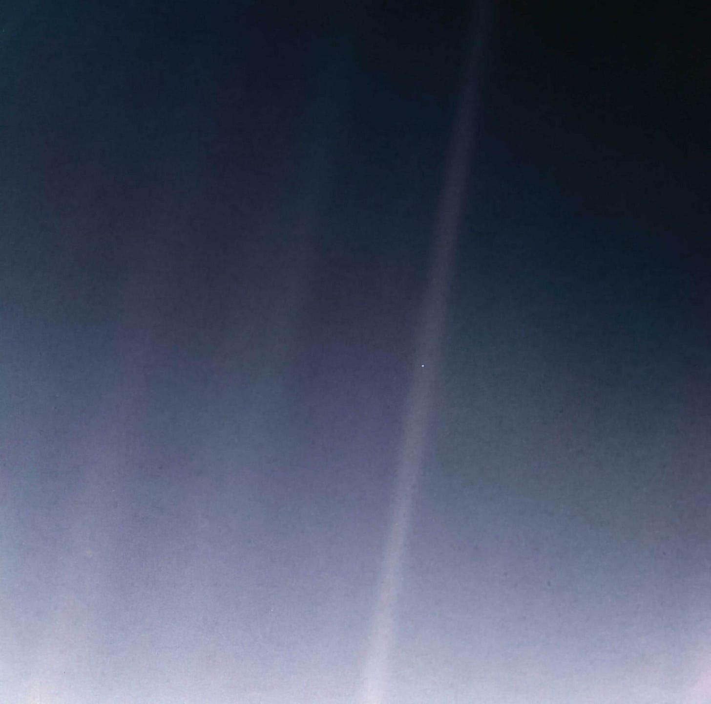 Earth appears as a tiny speck of light suspended in a sunbeam against the vastness of space. Earth appears as a tiny speck of light suspended in a sunbeam against the vastness of space.