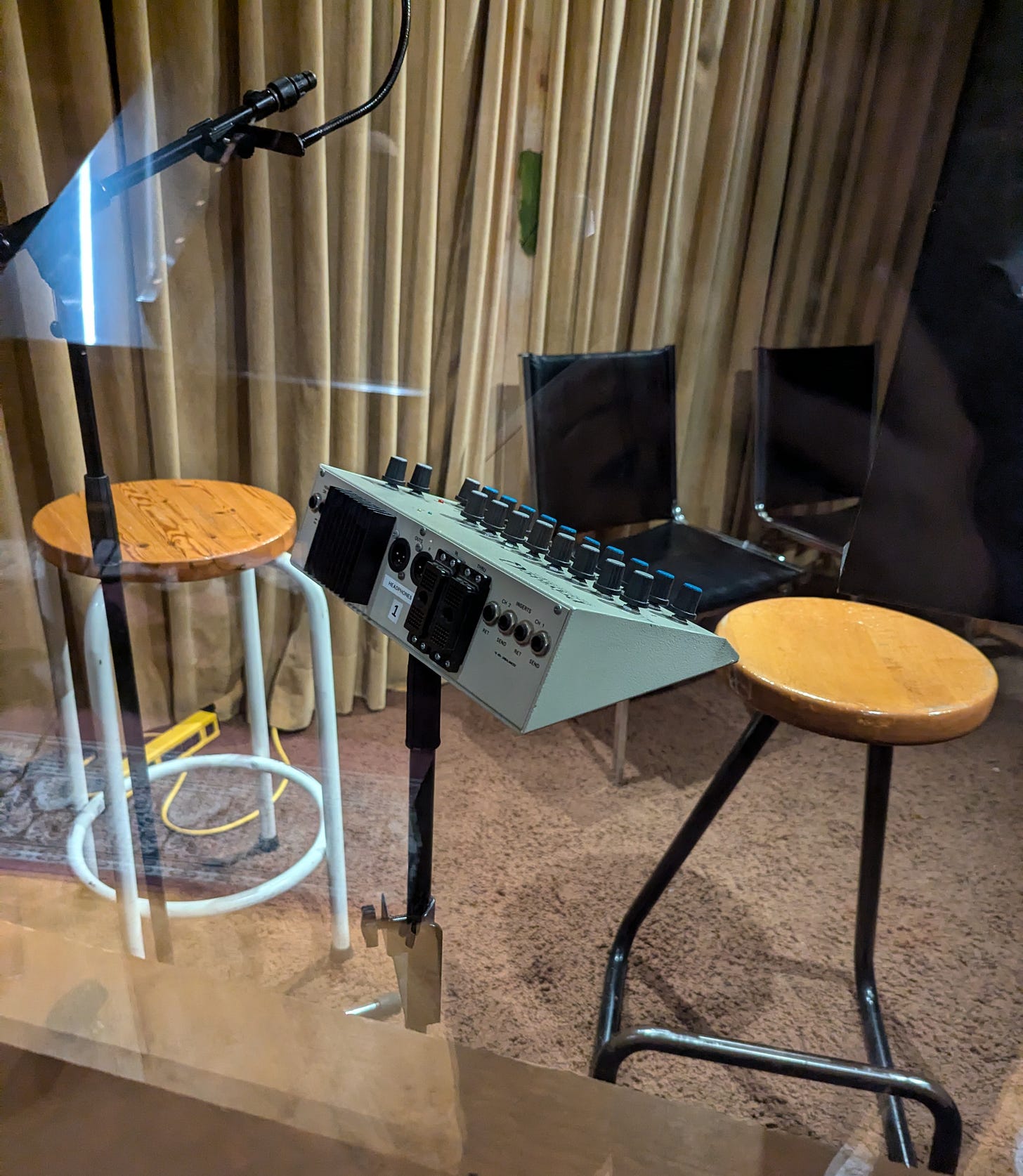 a small sound console, stools, chairs, and a microphone.