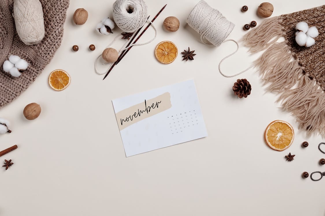 Free A Piece of a Calendar on the Table Top with Yarn Rolls and Sliced Fruits Stock Photo